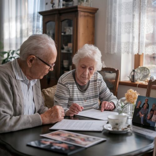 91-jährige Dame und ihr Mieter betrachten Dokumente am Wohnzimmertisch
